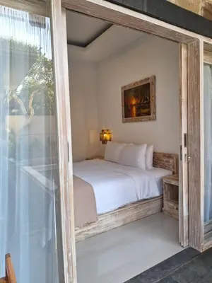 a bedroom with a bed and a sliding glass door at Casa Benoa Homestay in Nusa Dua