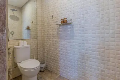a bathroom with a toilet and a tiled wall at Villa Odil, Great Value 700m beach & 15m pool in Seminyak