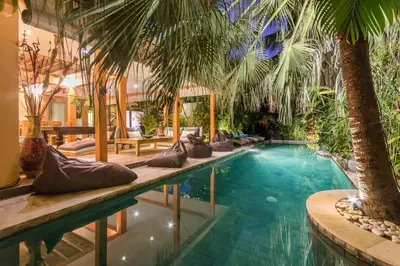 a swimming pool with palm trees in a resort at Villa Odil, Great Value 700m beach & 15m pool in Seminyak