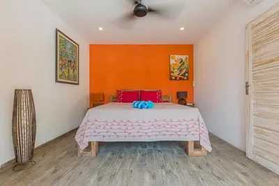 a bedroom with a large bed with an orange wall at Villa Odil, Great Value 700m beach & 15m pool in Seminyak