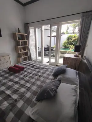 a bedroom with a bed with pillows and a window at Kubusawah Guest House in Seminyak