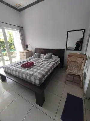 a bedroom with a bed and a mirror and a chair at Kubusawah Guest House in Seminyak