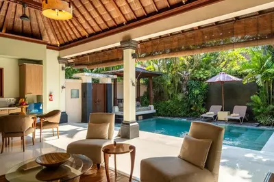 an outdoor living room with a pool and a villa at Villa Elegant by Exotiq in Seminyak