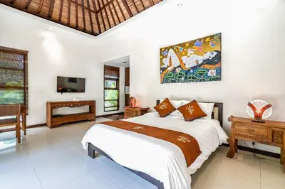 a bedroom with a large bed and a tv at Panatai Villa in Sanur