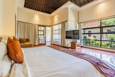 a bedroom with a large bed and a television at Panatai Villa in Sanur