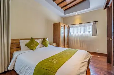 a bedroom with a large white bed with green pillows at Panatai Villa in Sanur