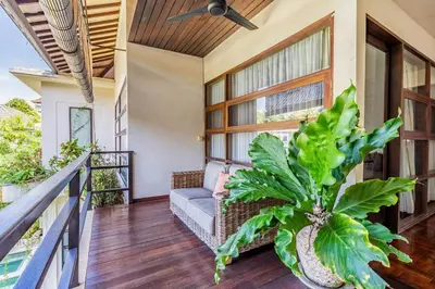 a porch with a couch and a plant at Panatai Villa in Sanur