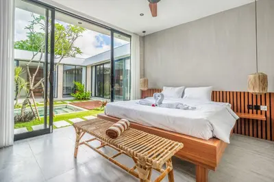 a bedroom with a large bed and a bench at Jimbaran Villa in Jimbaran