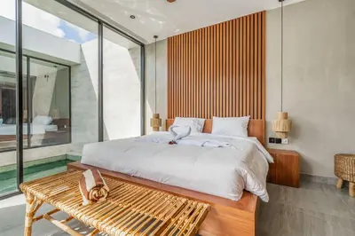 a bedroom with a large bed and a wooden bench at Jimbaran Villa in Jimbaran