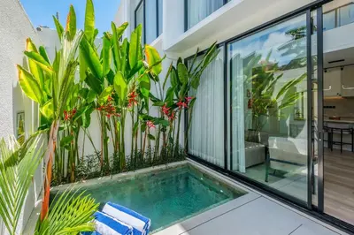 a swimming pool on the balcony of a house with plants at Layur Villa in Canggu