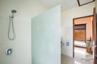 a white bathroom with a shower and a window at Villa Ayu in Kerobokan
