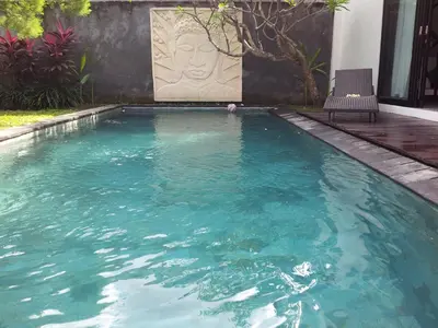 a swimming pool with blue water in front of a building at Villa Ayu in Kerobokan