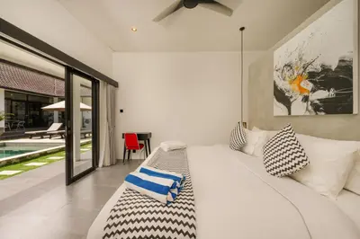 a bedroom with a white bed and a sliding glass door at Elegant Modern 4BR Retreat in the Heart of Berawa in Canggu
