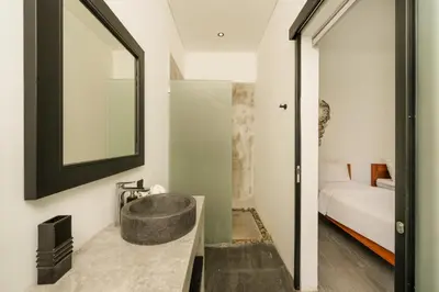 a bathroom with a sink and a mirror and a bed at Elegant Modern 4BR Retreat in the Heart of Berawa in Canggu
