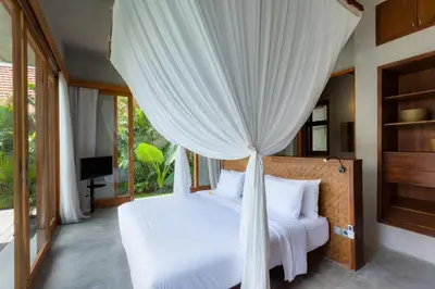 a bedroom with a white bed with a canopy at ZIN Berawa Villas & Bungalows in Canggu