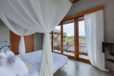 a bedroom with a bed with curtains and a balcony at ZIN Berawa Villas & Bungalows in Canggu
