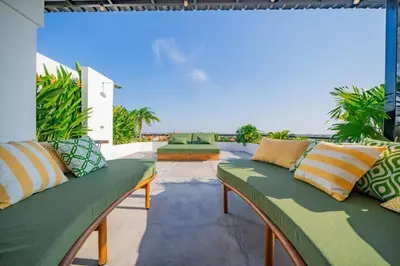 a patio with green couches and a view of the ocean at Luxury 4BR Villa Private Pool & Sea Horizon in Kerobokan