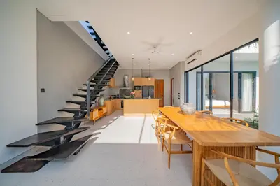 a dining room with a long table and a staircase at Luxury 4BR Villa Private Pool & Sea Horizon in Kerobokan