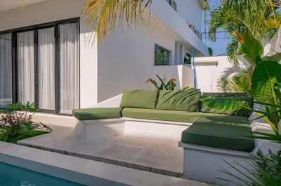 a living room with a couch next to a pool at Luxury 4BR Villa Private Pool & Sea Horizon in Kerobokan
