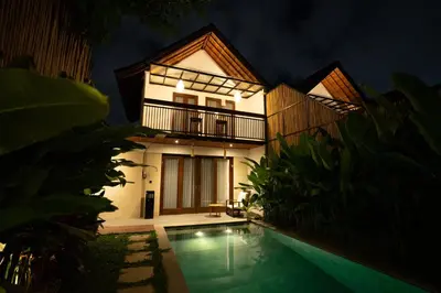 a villa with a swimming pool at night at De Awan Villa in Kerobokan