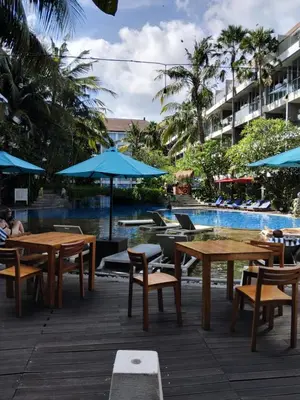 a patio with tables and chairs next to a pool at Sweet Condo in Seminyak