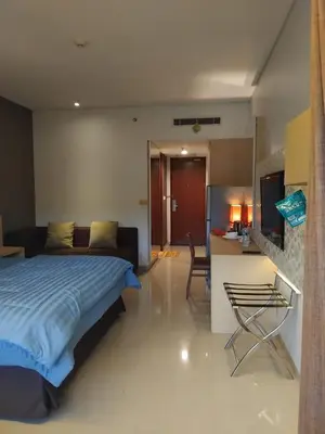 a bedroom with a bed and a kitchen and a table at Sweet Condo in Seminyak