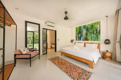 a bedroom with a large white bed and a chair at Spacious 5BR Modern Simplicity, Near Canggu's Best in Canggu