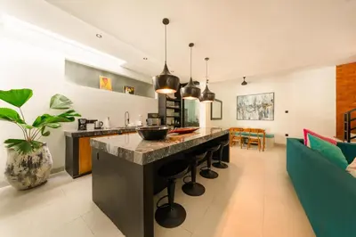 a kitchen and living room with a large island with stools at Spacious 5BR Modern Simplicity, Near Canggu's Best in Canggu