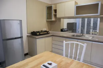 a kitchen with a refrigerator and a table with a chair at Sunrise Aventus Villa Nusa Dua in Nusa Dua
