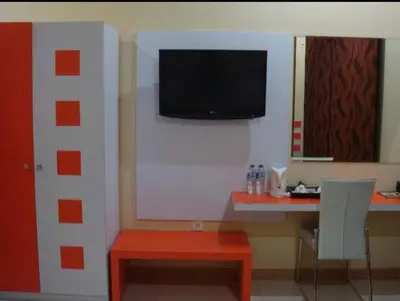 a room with a desk and a television on a wall at Mutiara Mansion Aparthotel in Seminyak