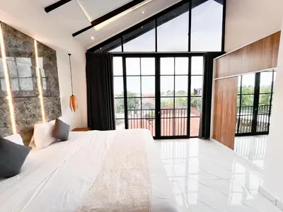 a bedroom with a large bed and large windows at Villa Arti in Seminyak