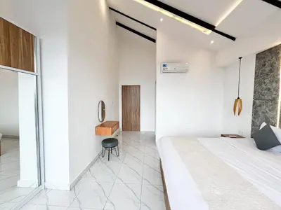a bedroom with white walls and a bed and a chair at Villa Arti in Seminyak