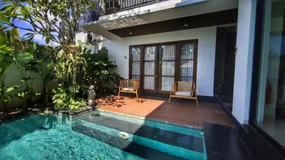 a house with a swimming pool and two chairs at Villa Lans By Baliem Villa in Jimbaran