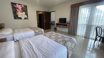 a hotel room with two beds and a television at Villa Lans By Baliem Villa in Jimbaran