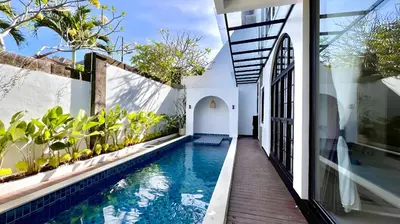 a house with a swimming pool next to a building at Villa Lans By Baliem Villa in Jimbaran