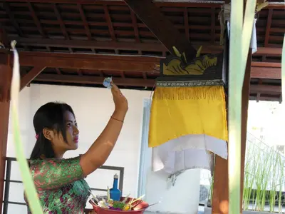 a woman is washing a hanging towel at HK Villa Bali in Legian