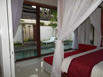 a bedroom with a view of a pool and a bed at HK Villa Bali in Legian
