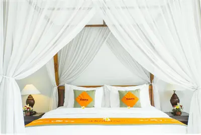 a bedroom with a white canopy bed with white curtains at Abimanyu Villa 2 Seminyak in Seminyak