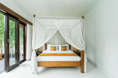 a bedroom with a canopy bed with white curtains at Abimanyu Villa 2 Seminyak in Seminyak