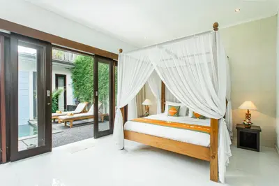 a bedroom with a canopy bed and a patio at Abimanyu Villa 2 Seminyak in Seminyak