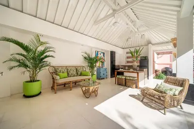 a living room with a couch and palm trees at Ocean Two 1BR Villa Honeymoon Seminyak in Seminyak