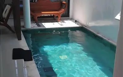 a pool of water with a chair next to it at Serene Bali Villa with Private Pool and Antiqued Charm in Balian