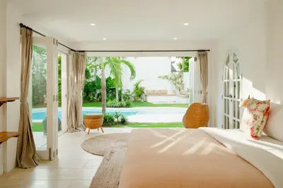 a bedroom with a bed and a view of a pool at Luxurious & Bespoke Upscale 3BR Villa in Canggu in Canggu