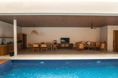 a house with a swimming pool and a dining room at Kinama Villa Jimbaran Bali in Jimbaran