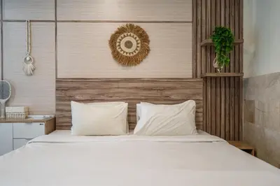 a bedroom with a bed with white sheets at Puri Ratu Jimbaran Villa by Betterplace in Jimbaran