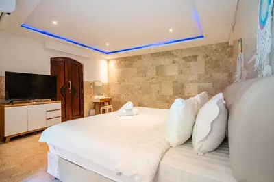 a bedroom with a large white bed with a flat screen tv at Puri Ratu Jimbaran Villa by Betterplace in Jimbaran