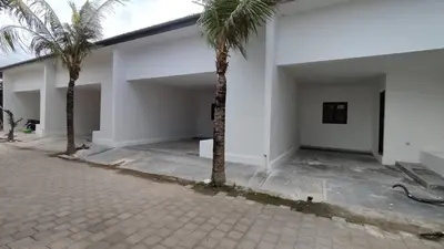 a white building with two palm trees in the courtyard at Mopoe Guesthouse in Sanur