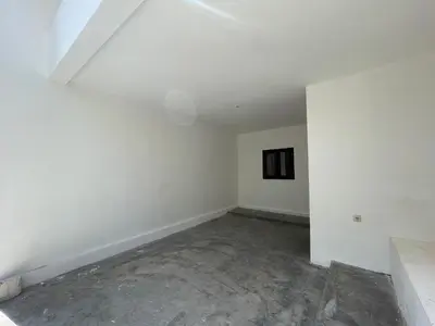 an empty room with white walls and a concrete floor at Mopoe Guesthouse in Sanur