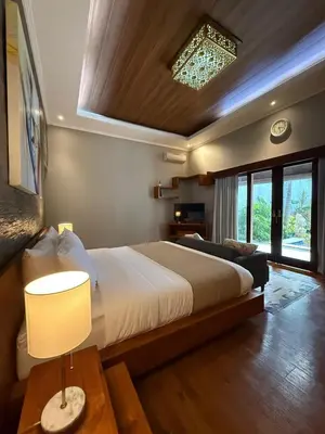 a bedroom with a bed and a lamp on a table at Villa Jiwanta by Maheswara in Kerobokan