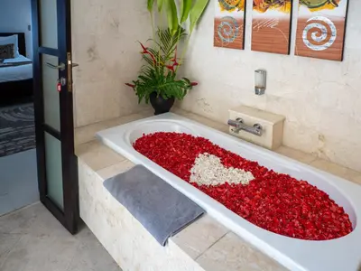 a bath tub filled with red flowers in a bathroom at Villa Cometa Luxury Seminyak by Adam Jyota Management in Seminyak